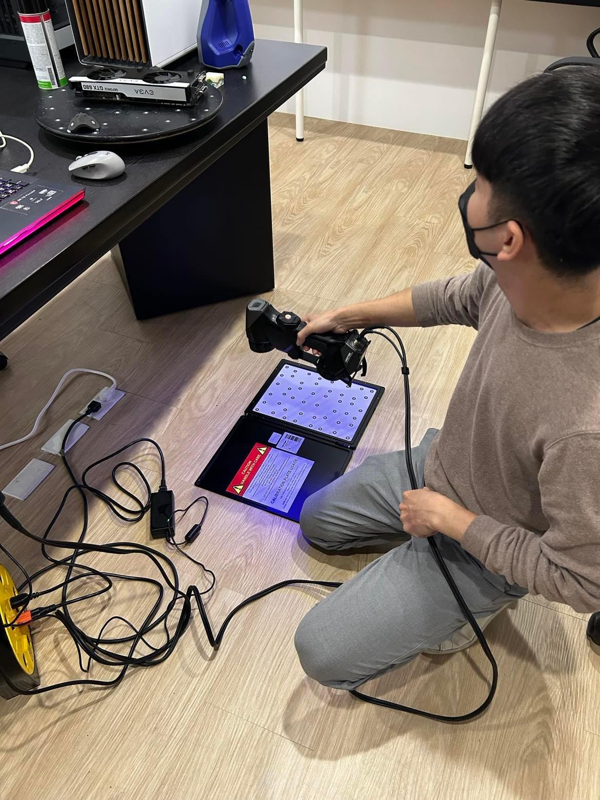 男子手持3D掃描器對準校準板