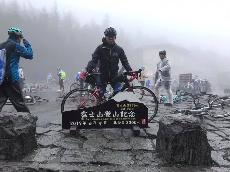 富士山五合目，單車手與登山紀念牌合影