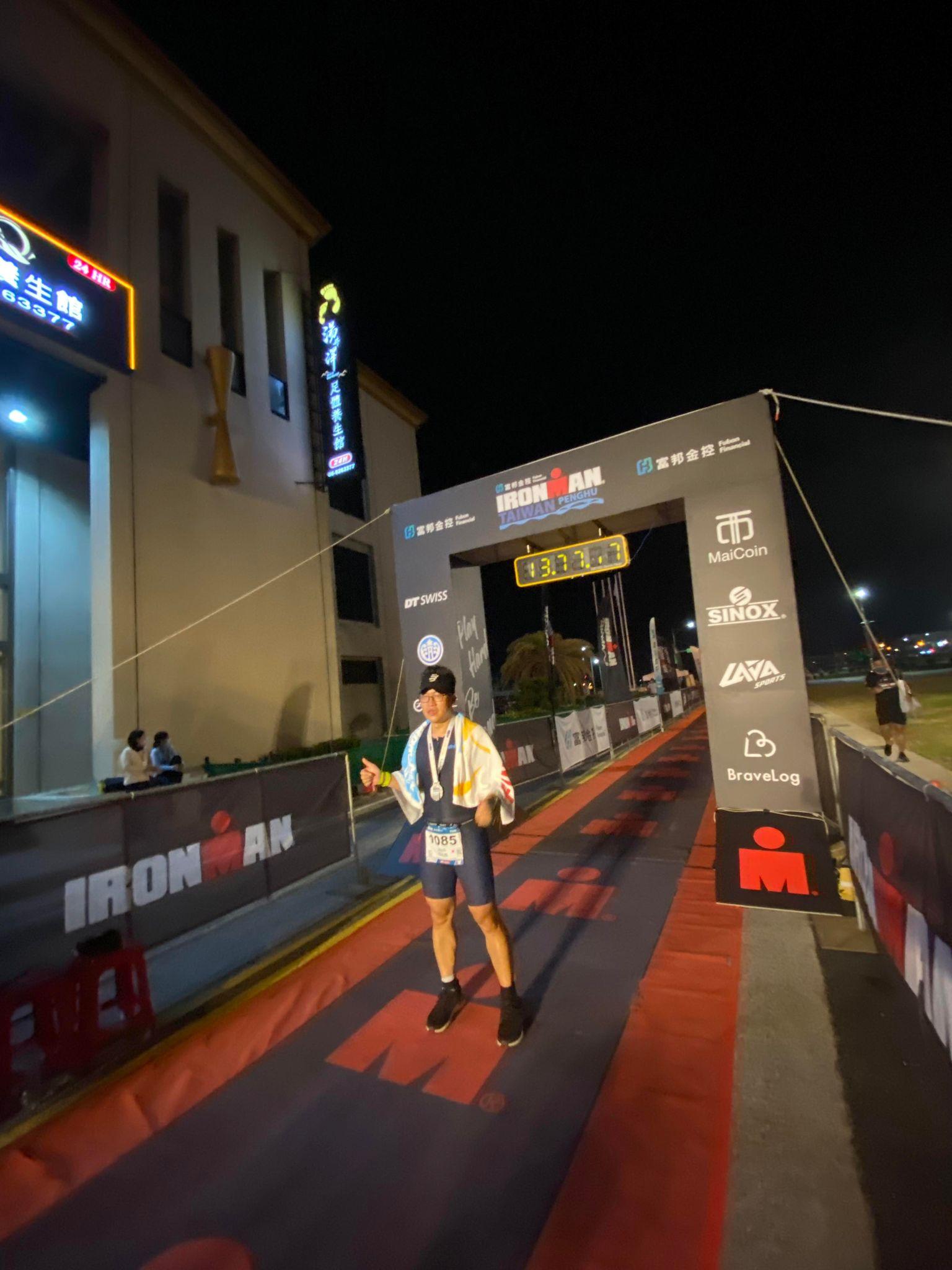 鐵人三項選手在IRONMAN終點線比讚慶祝