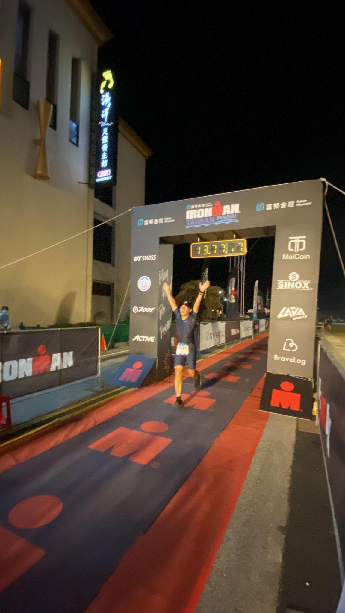 選手高舉雙手衝過IRONMAN終點線，計時器