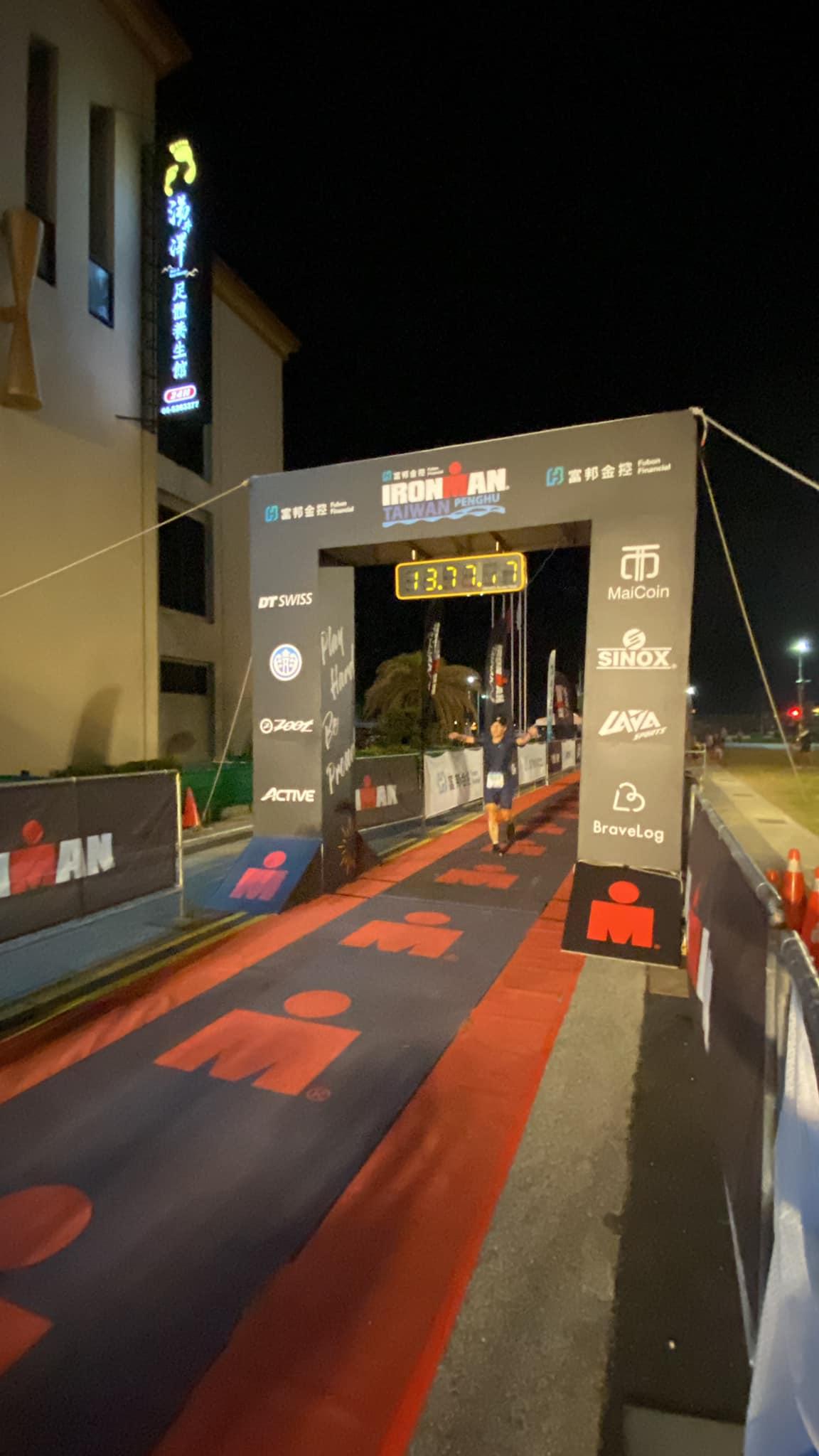 選手在夜晚衝過澎湖IRONMAN終點線，計時器顯示13.7