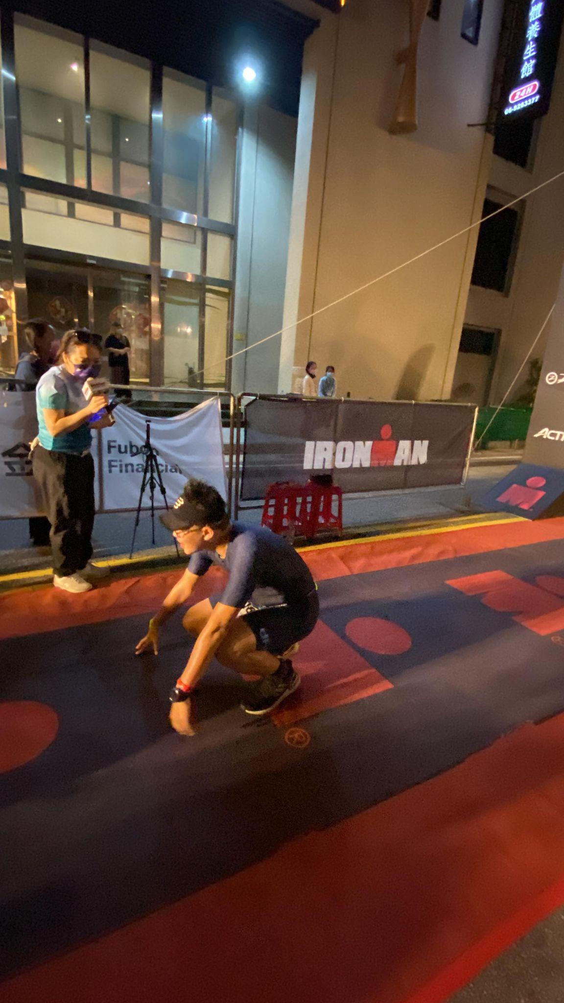 鐵人三項選手在IRONMAN終點線前蹲下休息
