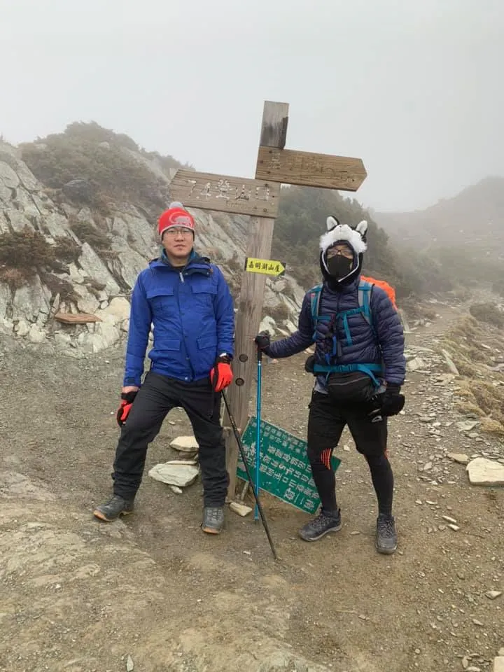 兩位登山者在嘉明湖山屋指示牌旁合影