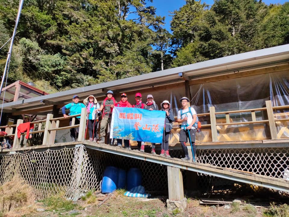 一群登山隊員在山屋木棧道上合照，手持鳳凰山