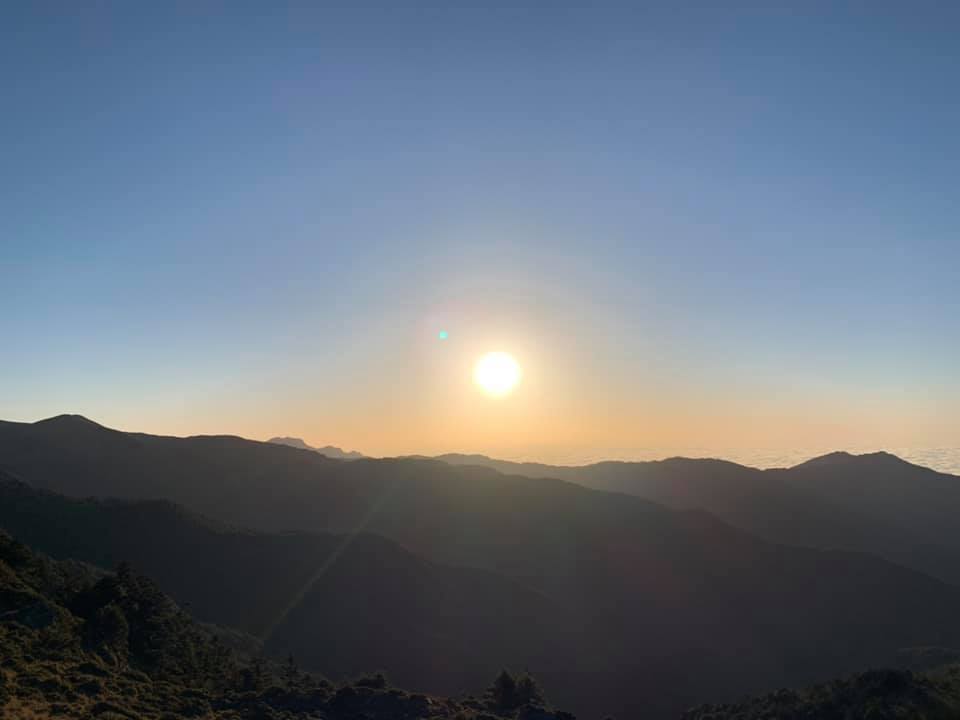 太陽在山脈上空，山巒剪影清晰可見